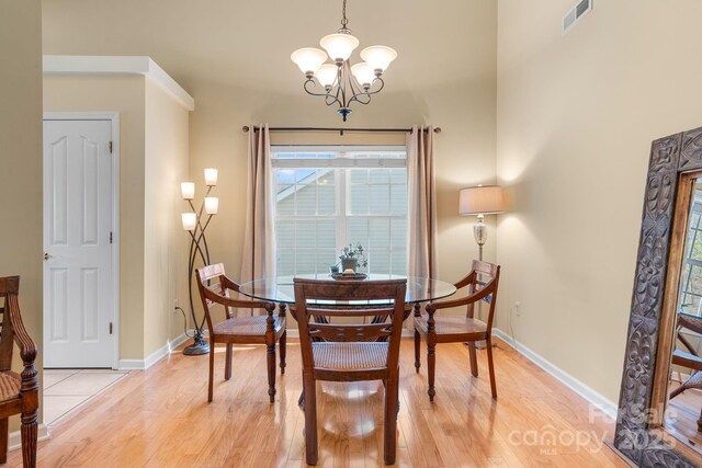 dining room featuring visible vents, baseboards, a notable chandelier, and light wood finished floors