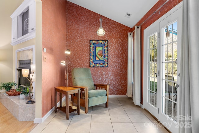 sitting room featuring visible vents, wallpapered walls, baseboards, vaulted ceiling, and light tile patterned floors