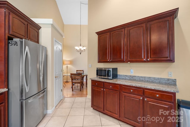 kitchen with light tile patterned floors, stainless steel appliances, an inviting chandelier, and reddish brown cabinets