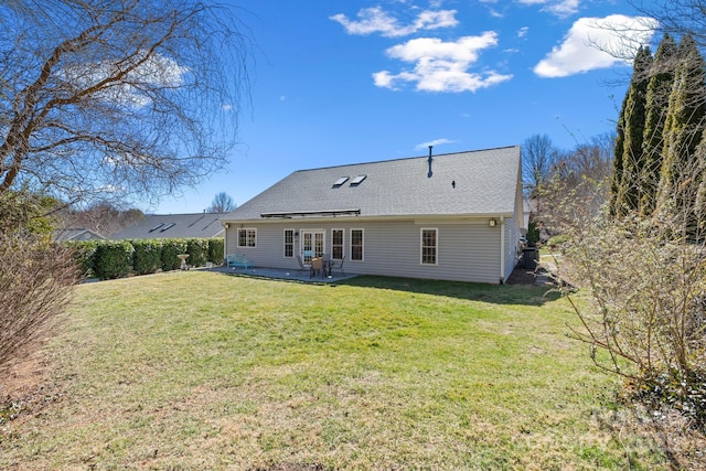 rear view of house with a lawn, a shingled roof, and a patio