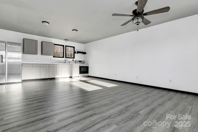 unfurnished living room featuring sink, light hardwood / wood-style flooring, and ceiling fan