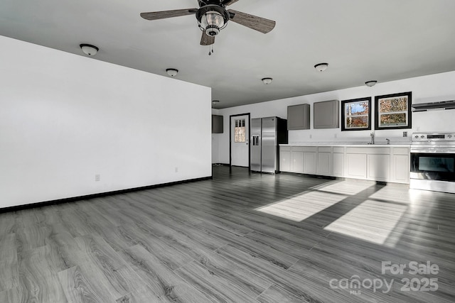 unfurnished living room with ceiling fan, sink, and light wood-type flooring