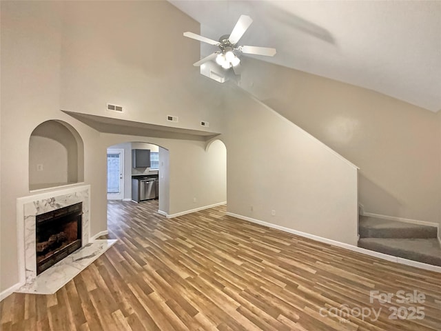 unfurnished living room with wood-type flooring, high vaulted ceiling, a premium fireplace, and ceiling fan