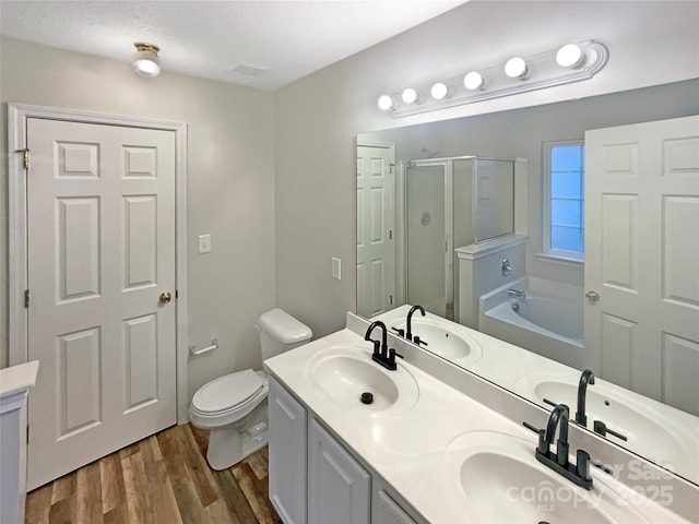 full bathroom featuring hardwood / wood-style flooring, separate shower and tub, vanity, a textured ceiling, and toilet