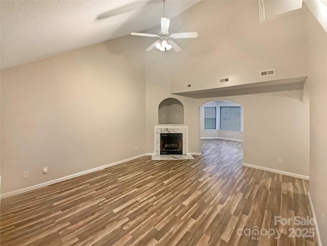 unfurnished living room featuring dark hardwood / wood-style floors, ceiling fan, a fireplace, and high vaulted ceiling