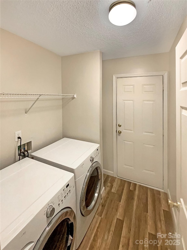 clothes washing area featuring washing machine and clothes dryer, hardwood / wood-style floors, and a textured ceiling