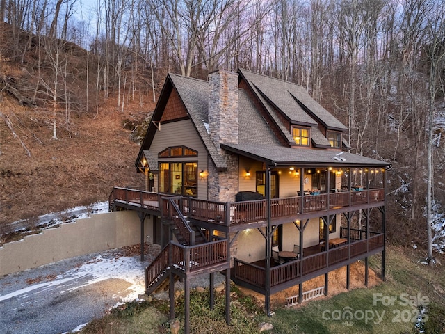 snow covered back of property featuring a wooden deck