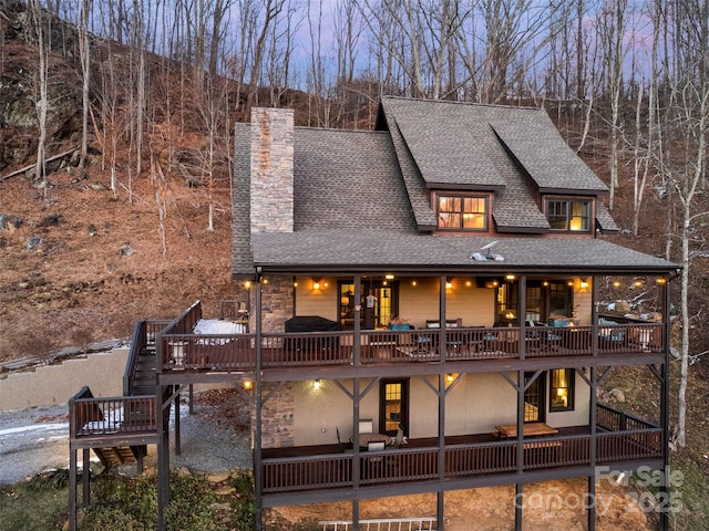 back house at dusk featuring a wooden deck