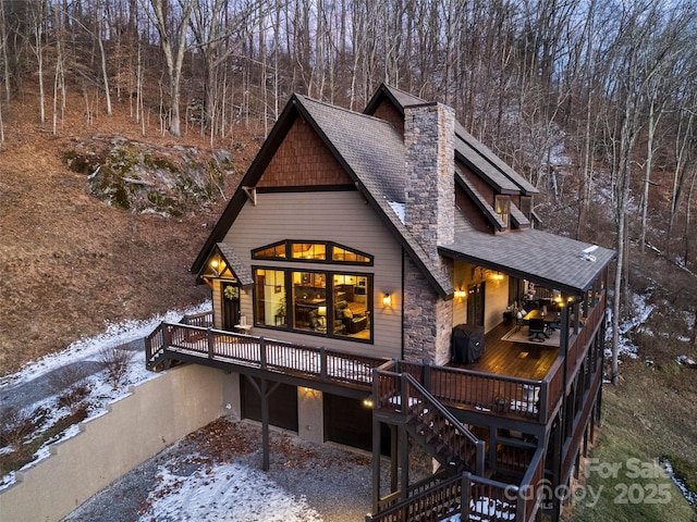 snow covered rear of property featuring a wooden deck