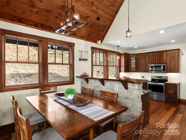 dining area with dark wood-type flooring, vaulted ceiling, and wooden ceiling