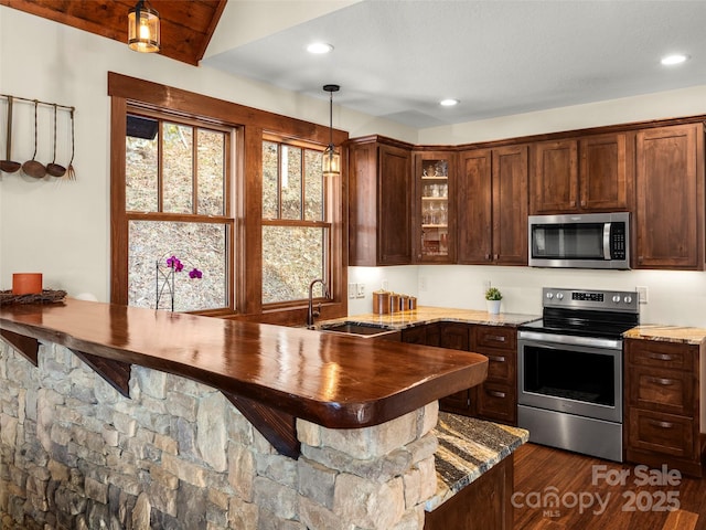 kitchen with pendant lighting, sink, stainless steel appliances, dark hardwood / wood-style flooring, and kitchen peninsula