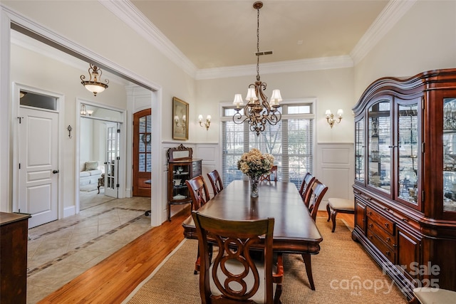 dining space featuring an inviting chandelier, ornamental molding, and light wood-type flooring