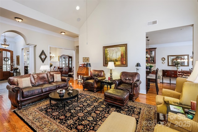 living room featuring high vaulted ceiling, hardwood / wood-style floors, and ornate columns