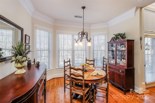 dining area featuring ornamental molding, an inviting chandelier, and light wood-type flooring