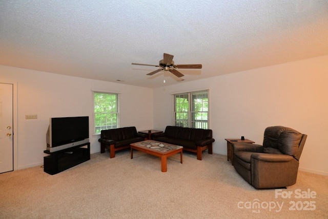 carpeted living room featuring ceiling fan and a textured ceiling