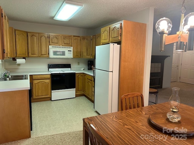 kitchen featuring pendant lighting, sink, white appliances, and a textured ceiling