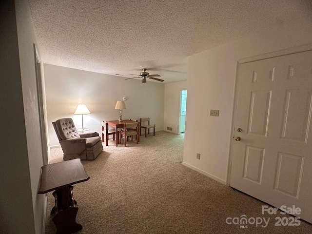 sitting room featuring ceiling fan, a textured ceiling, and carpet flooring