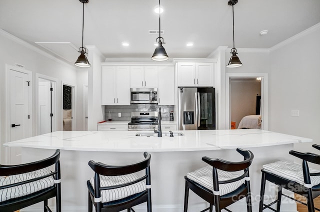 kitchen featuring a large island with sink, appliances with stainless steel finishes, and hanging light fixtures