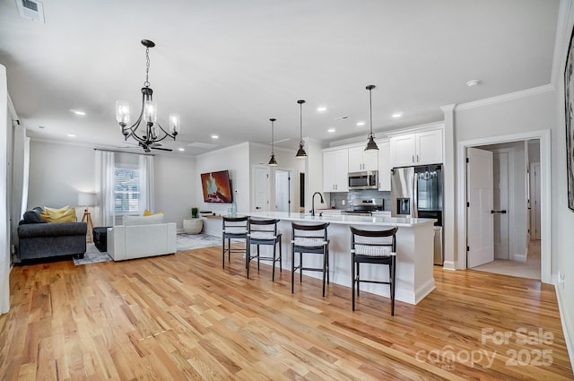 kitchen with white cabinetry, stainless steel appliances, a kitchen breakfast bar, and hanging light fixtures