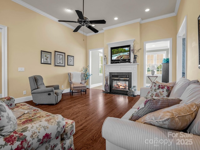 living room featuring a tile fireplace, dark hardwood / wood-style floors, ceiling fan, and crown molding