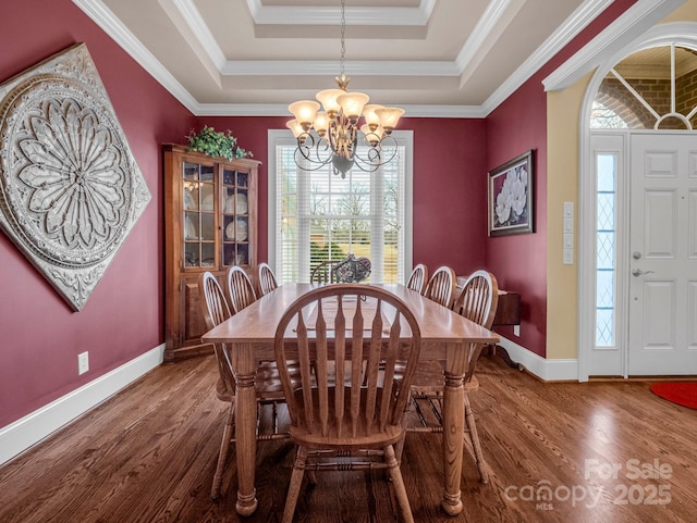 dining space with a notable chandelier, hardwood / wood-style flooring, ornamental molding, and a raised ceiling