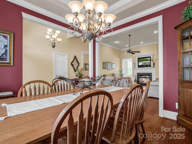 dining space featuring crown molding, a fireplace, dark hardwood / wood-style floors, and ceiling fan with notable chandelier