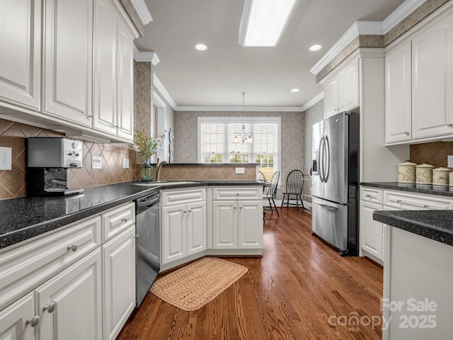 kitchen featuring stainless steel appliances, white cabinetry, ornamental molding, and pendant lighting