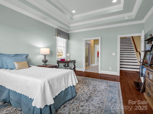 bedroom featuring crown molding, dark wood-type flooring, connected bathroom, and a tray ceiling