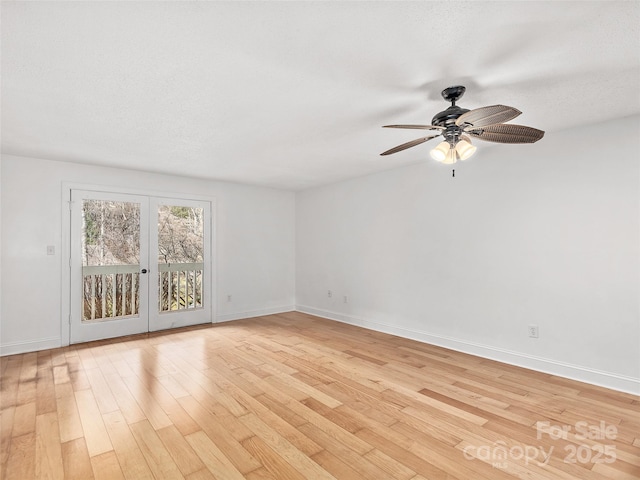 empty room featuring baseboards, french doors, a textured ceiling, and light wood-style floors