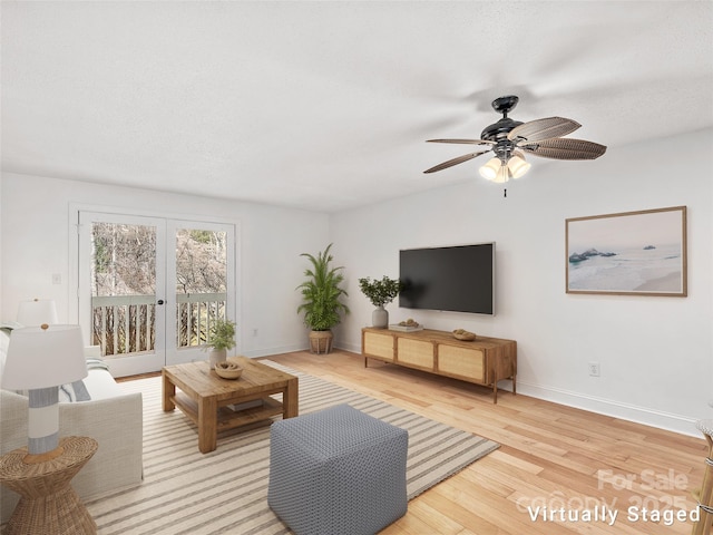 living room featuring a ceiling fan, light wood-type flooring, french doors, and baseboards