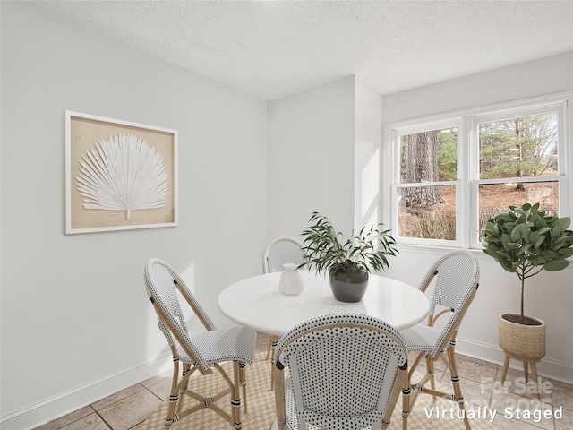 dining area featuring a textured ceiling, light tile patterned flooring, and baseboards