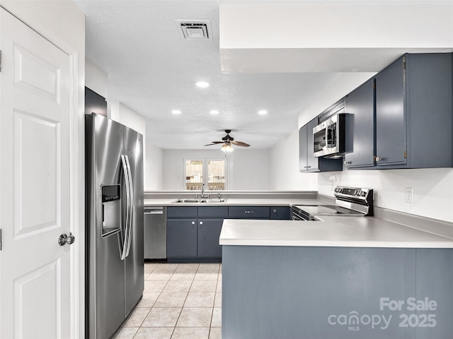 kitchen with a peninsula, a sink, visible vents, light countertops, and appliances with stainless steel finishes