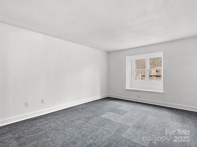 empty room with dark carpet, a textured ceiling, and baseboards