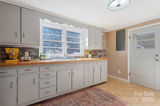 kitchen featuring butcher block counters, sink, decorative backsplash, and electric panel