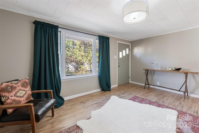 sitting room with ornamental molding and light hardwood / wood-style flooring