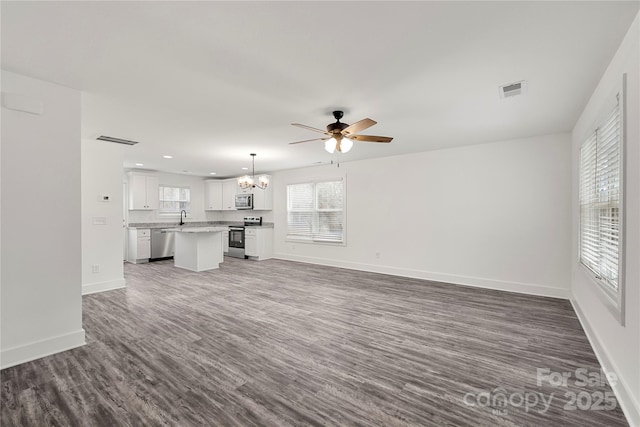 unfurnished living room featuring sink, dark hardwood / wood-style flooring, and ceiling fan with notable chandelier