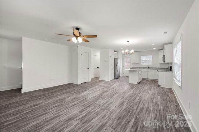 unfurnished living room featuring dark wood-type flooring and ceiling fan with notable chandelier