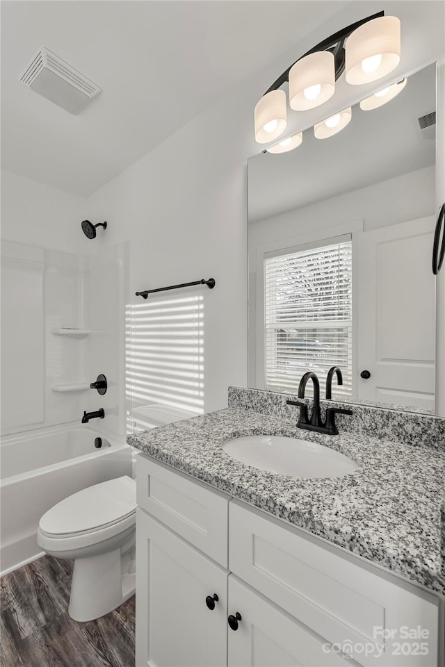 full bathroom with vanity, hardwood / wood-style flooring, toilet, and washtub / shower combination