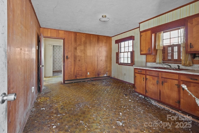 kitchen featuring wood walls, sink, a baseboard heating unit, crown molding, and a textured ceiling