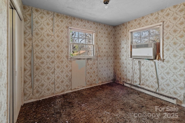 spare room featuring cooling unit, a baseboard heating unit, plenty of natural light, and a textured ceiling