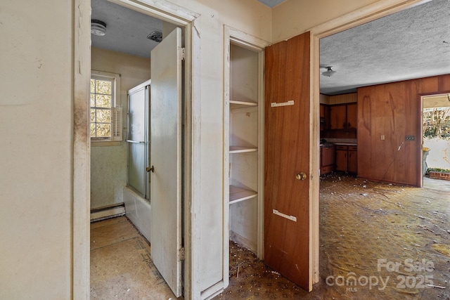 corridor with a baseboard heating unit, a textured ceiling, and wooden walls