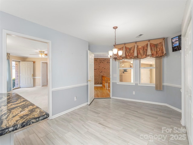 unfurnished dining area with visible vents, baseboards, and ceiling fan with notable chandelier