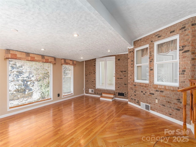 unfurnished living room featuring visible vents, a textured ceiling, and light wood-style floors