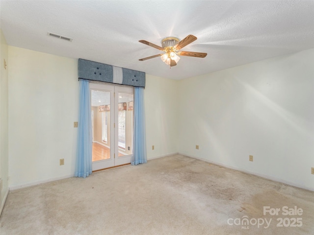 spare room featuring ceiling fan, carpet, visible vents, and a textured ceiling