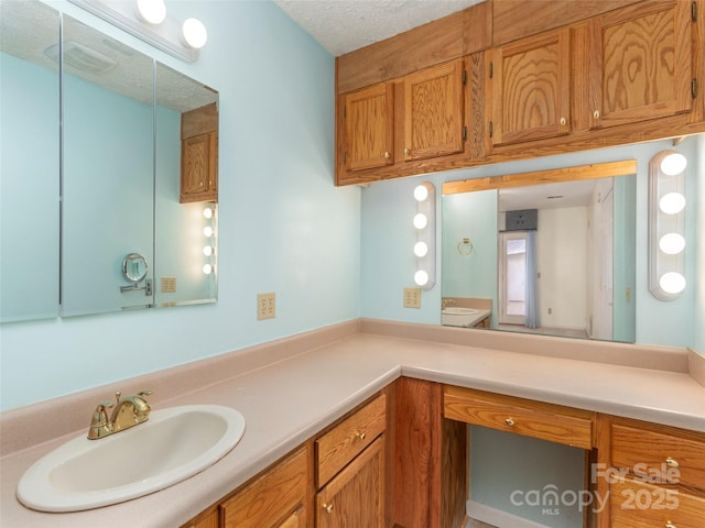 bathroom featuring visible vents, toilet, vanity, and a textured ceiling