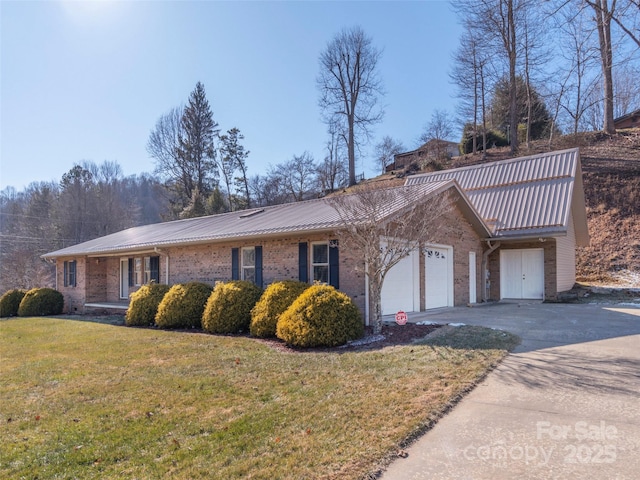 view of front facade with concrete driveway, a front yard, an attached garage, metal roof, and brick siding