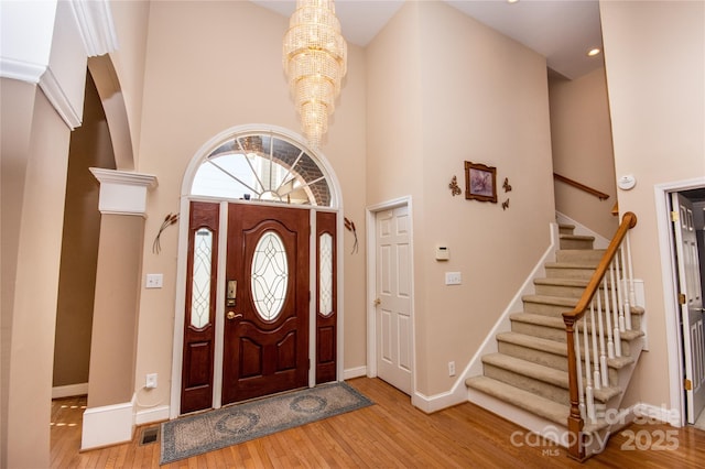 entryway featuring a towering ceiling, a notable chandelier, and light hardwood / wood-style flooring