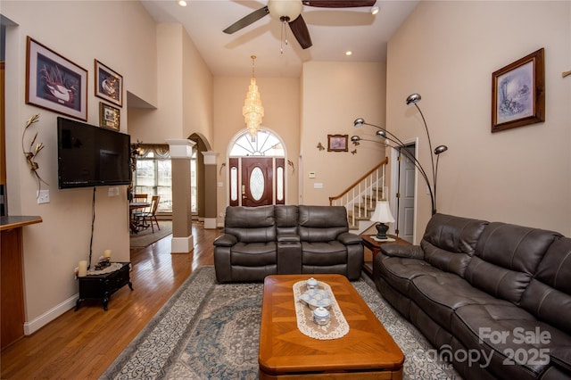 living room featuring ornate columns, ceiling fan, hardwood / wood-style floors, and a high ceiling