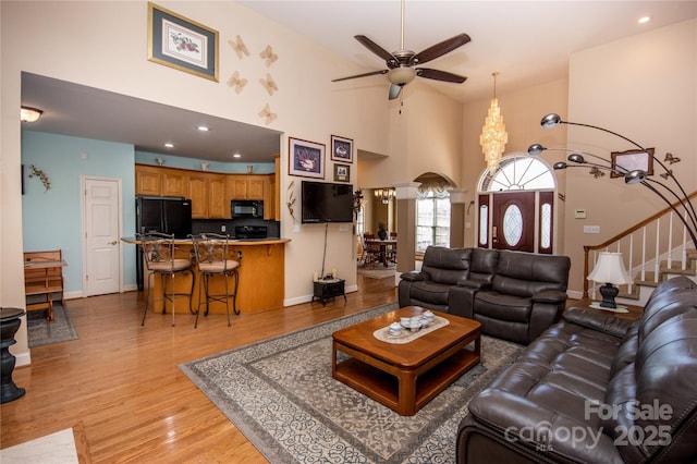 living room featuring ceiling fan, high vaulted ceiling, and light hardwood / wood-style flooring