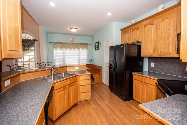 kitchen featuring tasteful backsplash, sink, light wood-type flooring, and black appliances